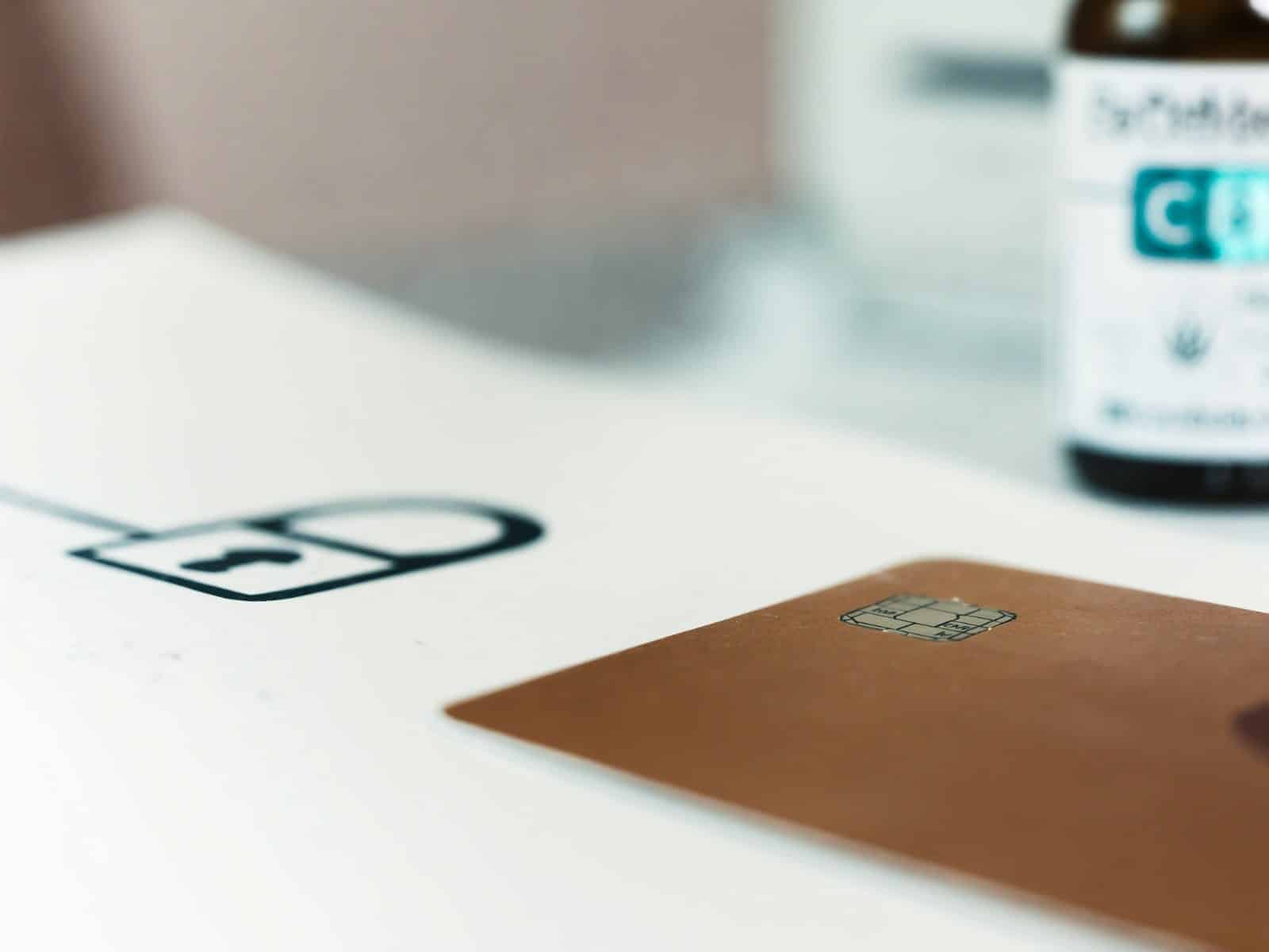 Kreditkarte neben einem Schloss-Symbol auf hellem Tisch, im Hintergrund ein CBD-Produkt – Sinnbild für gesperrte Zahlungswege